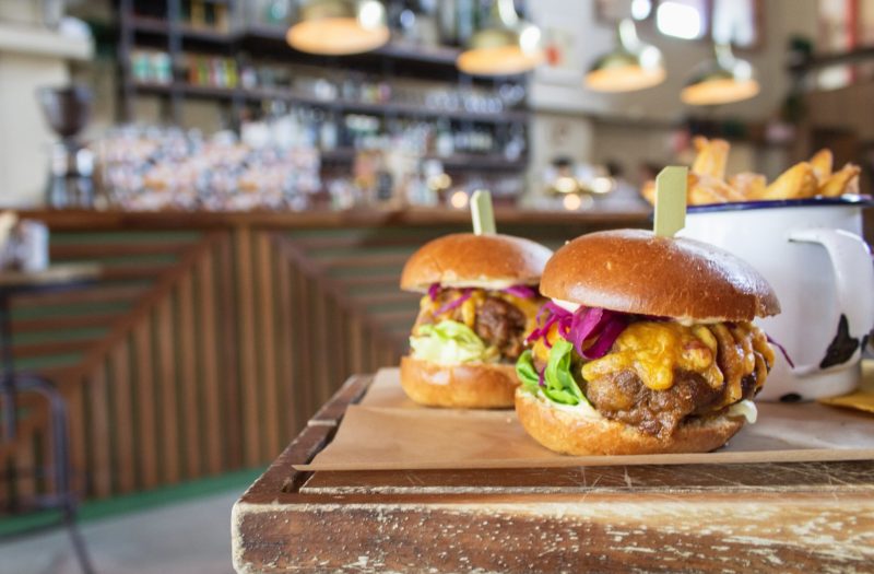 A closeup of hamburgers on a wooden tray with a blurred background