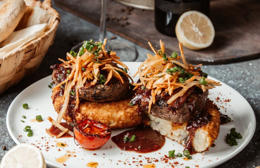 potato patties topped with beef patties and shoe strings
